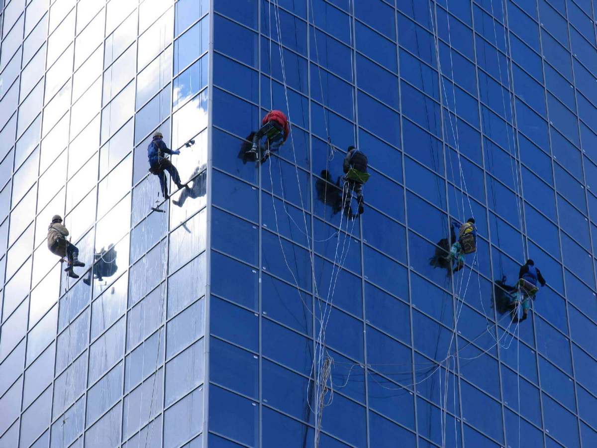 Альпинисты на высоком здании моют окна